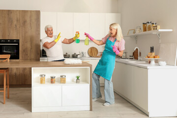 Mature couple having fun while cleaning in kitchen