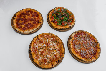 Pizza set with meat and cheese. Pepperoni pizza with arugula and prosciutto. Meat pizza with cheese, cherry tomatoes and hot peppers on a white background