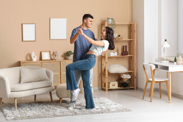 Happy young couple dancing in living room