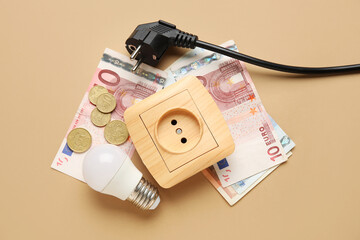 Electric power plug and socket with light bulb and money on brown background