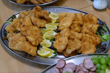 Chicken cutlets with lemon on a stainless tray.