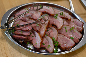 Slices of baked meat on a metal tray.