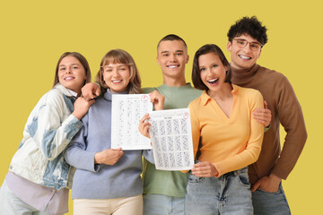 Fototapeta premium Group of students with results of exam on yellow background