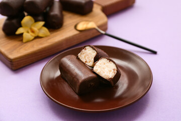 Plate with tasty chocolate glazed curd snacks with vanilla flavor on lilac background