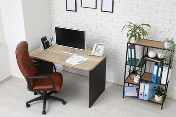 Interior of stylish office with workplace, armchair, modern computer and shelving unit