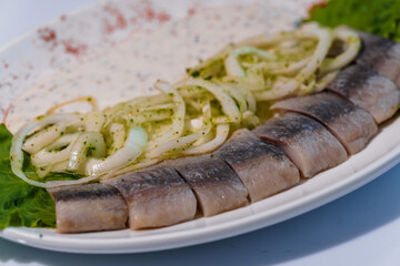 Herring fish with pickled onions and sauce on a white plate
