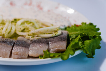Herring fish with pickled onions and sauce on a white plate