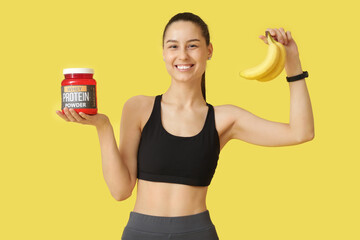 Sporty young happy woman with jar of protein powder and bananas on yellow background