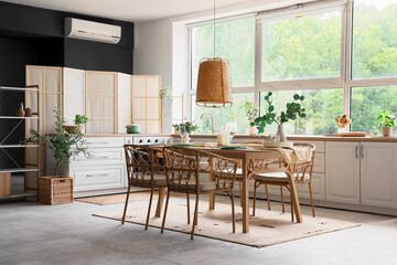 Served dining table with chairs and hanging lamp in interior of kitchen