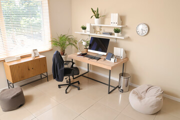 Stylish interior of office with workplace, modern computer and armchair