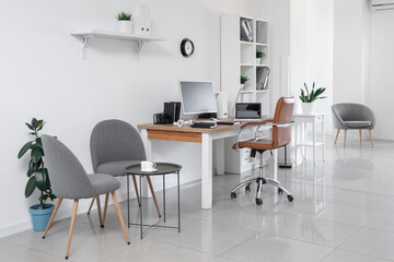 Stylish interior of light office with workplace, modern computer, laptop and armchair