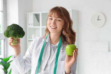 Female nutritionist with broccoli and apple in office