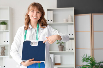 Female nutritionist pointing at weight scales in office