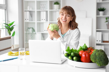 Female nutritionist with cabbage at table in office