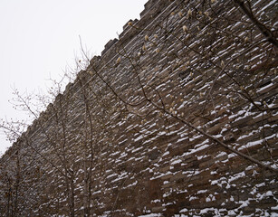 The tall stone outer wall of the Forbidden City, beijing, china partially covered in snow, with...