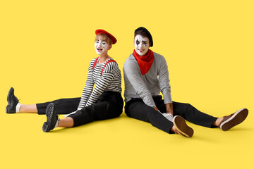 Couple of pantomimists sitting on yellow background