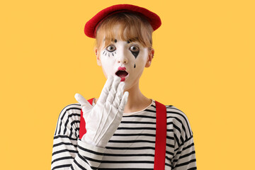Surprised female pantomimist on yellow background