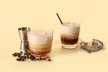 Glasses of White Russian cocktail and coffee beans on yellow background