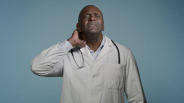 Overworked tired african american man doctor male surgeon medical worker feel neck pain muscle inflammation rubbing massaging nape suffering from ache feeling hurt stiff muscles studio blue background