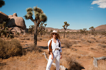 Adorable woman dressed in cowgirl style posing in Western Park, Joshua Tree, California