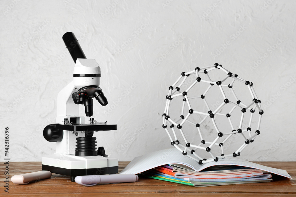 Wall mural modern microscope with copybooks and molecular model on wooden table against white grunge background