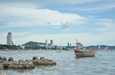 Sunset time at harbor. Beautiful sunset at tropical sea with small fishing boat isolated with cityscape view. Wooden boat with sunrise beach horizon background.