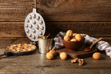 Composition with tasty walnut shaped cookies, boiled condensed milk and baking form on wooden background