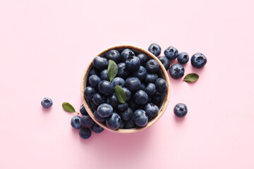 Bowl of fresh ripe blueberry on pink background, closeup