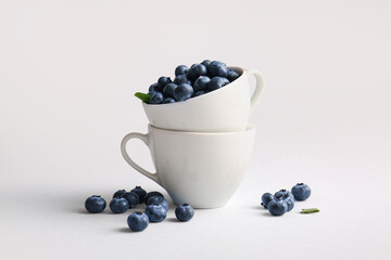 Cups of fresh ripe blueberry on white background