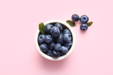 Bowl with fresh ripe blueberry on pink background, closeup