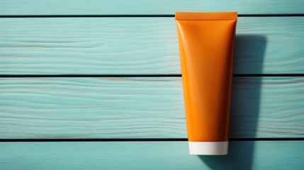Bright orange cosmetic tube on a turquoise wooden surface, perfect for beauty, skincare, or health product promotions.