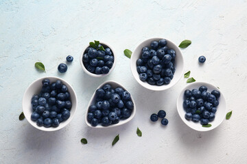 Bowls of fresh ripe blueberry on pale blue background