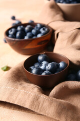 Napkin and bowls of fresh ripe blueberry on pink grunge background, closeup