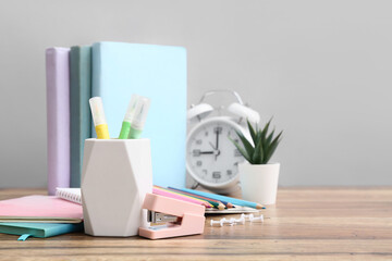 Different stationery on wooden table against grey wall
