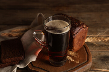 Glass of fresh kvass and bread on wooden background