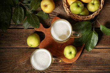 Glasses of fresh apple kvass and wicker basket with fruits on wooden background