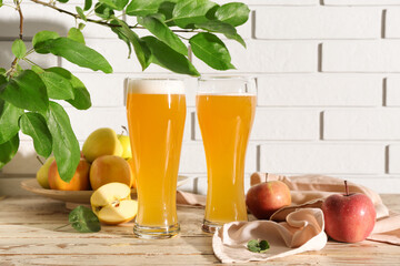 Glasses of fresh apple kvass and plate with fruits on white wooden table