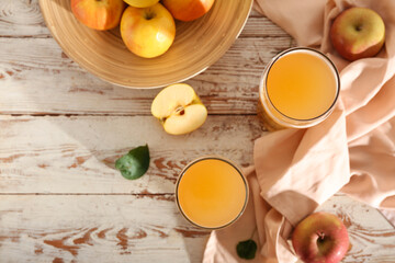 Glasses of fresh apple kvass and plate with fruits on white wooden background