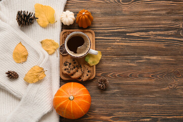 Composition with cup of coffee, cookies, warm sweater and autumn decor on wooden background