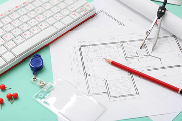 Architect's supplies with house plans and computer keyboard on green background, closeup