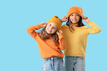 Cute little happy girls in autumn clothes on blue background