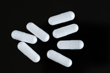 white vitamins supplement capsules over a black background