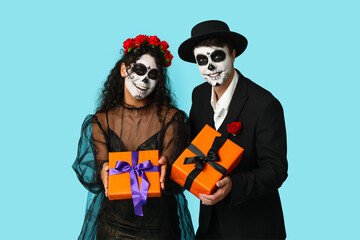 Young couple dressed for Halloween with gift boxes on blue background