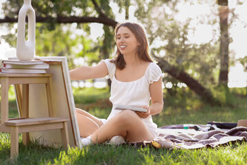 Young woman painting on canvas in park