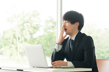 あくびをする若いビジネスマン
