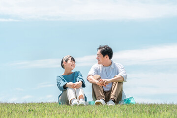 青空の見える公園・丘に座る家族・親子（父親・娘・シングルファーザー）
