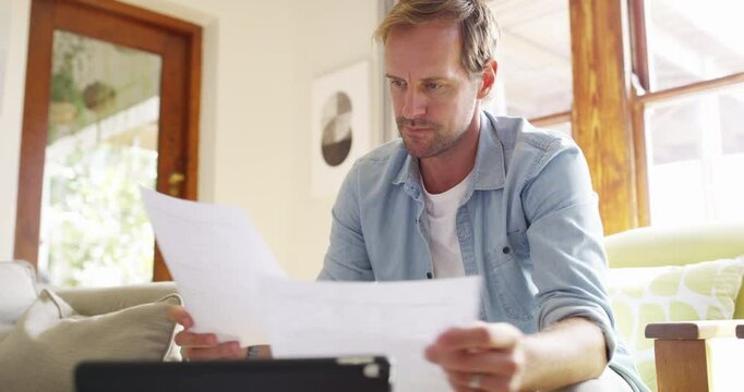 Man, reading documents and bills on sofa for financial planning, asset management or taxes on tablet at home. Person thinking of budget, insurance paperwork and invoice or receipt for loan payment