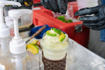 Avocado smoothie garnished with avocado slices and parsley leaves.  In takeaway cup Fruit smoothies rich in good fats, vitamins, healthy drinks.