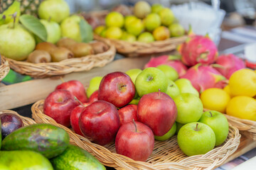 Various fruits on shelves and in wicker baskets, red apples, green apples, dragon fruit, avocados, oranges, kiwis, guavas, lemons, and colorful fruits. rich in vitamins Eating fruit for good health.