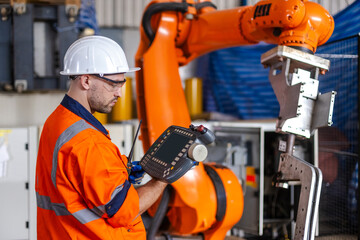 man engineer using remote robot controller operate standing at automation robot arms machine in...